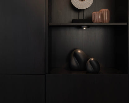 Sfeerfoto van de kleine donkerblauwe Embrace urn in een kast – modern Nederlands design