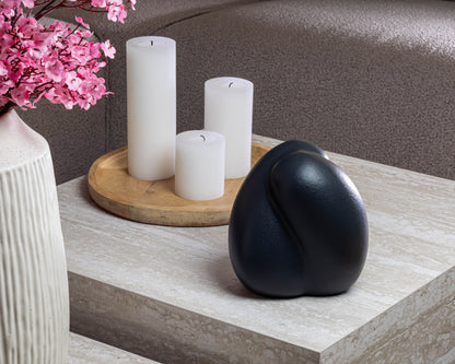 Sfeerfoto van de kleine donkerblauwe Embrace urn op een tafel – modern Nederlands design
