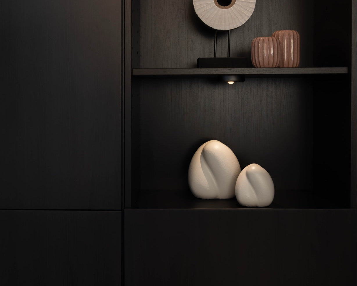 Sfeerfoto van de kleine witte Embrace urn in een kast – modern Nederlands design